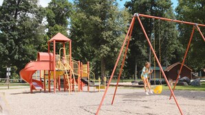 Une aire de jeux avec un toboggan, des balançoires et une structure d’escalade.