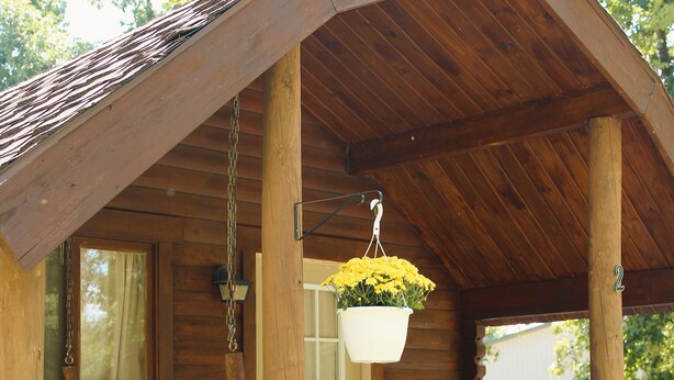 Une cabane en bois avec un porche, un pot de fleurs suspendu et une porte portant le numéro « 2 ».
