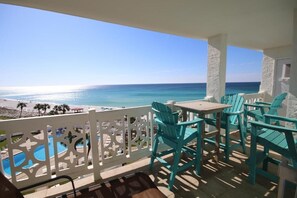 Ein Balkon mit türkisfarbenen Stühlen und Blick aufs Meer.