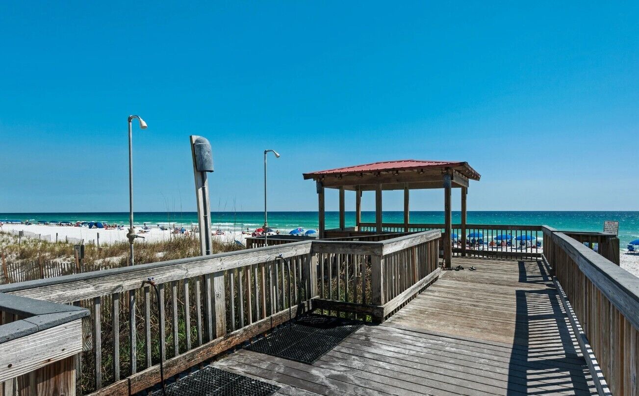 A wooden boardwalk leading to a beach with a gazebo.