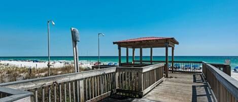 A wooden boardwalk leading to a beach with a gazebo.
