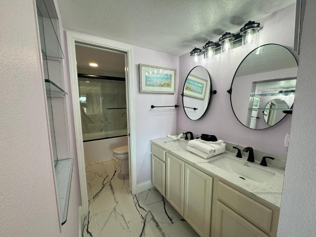 A bathroom with a vanity, two mirrors, a sink, and a shower area.