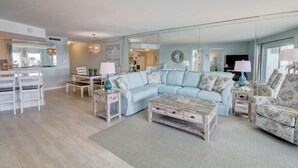 A spacious living area with a light blue sofa, a coffee table, and a dining table with chairs.
