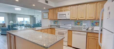 A modern kitchen with wooden cabinets, a granite countertop, and stainless steel appliances.