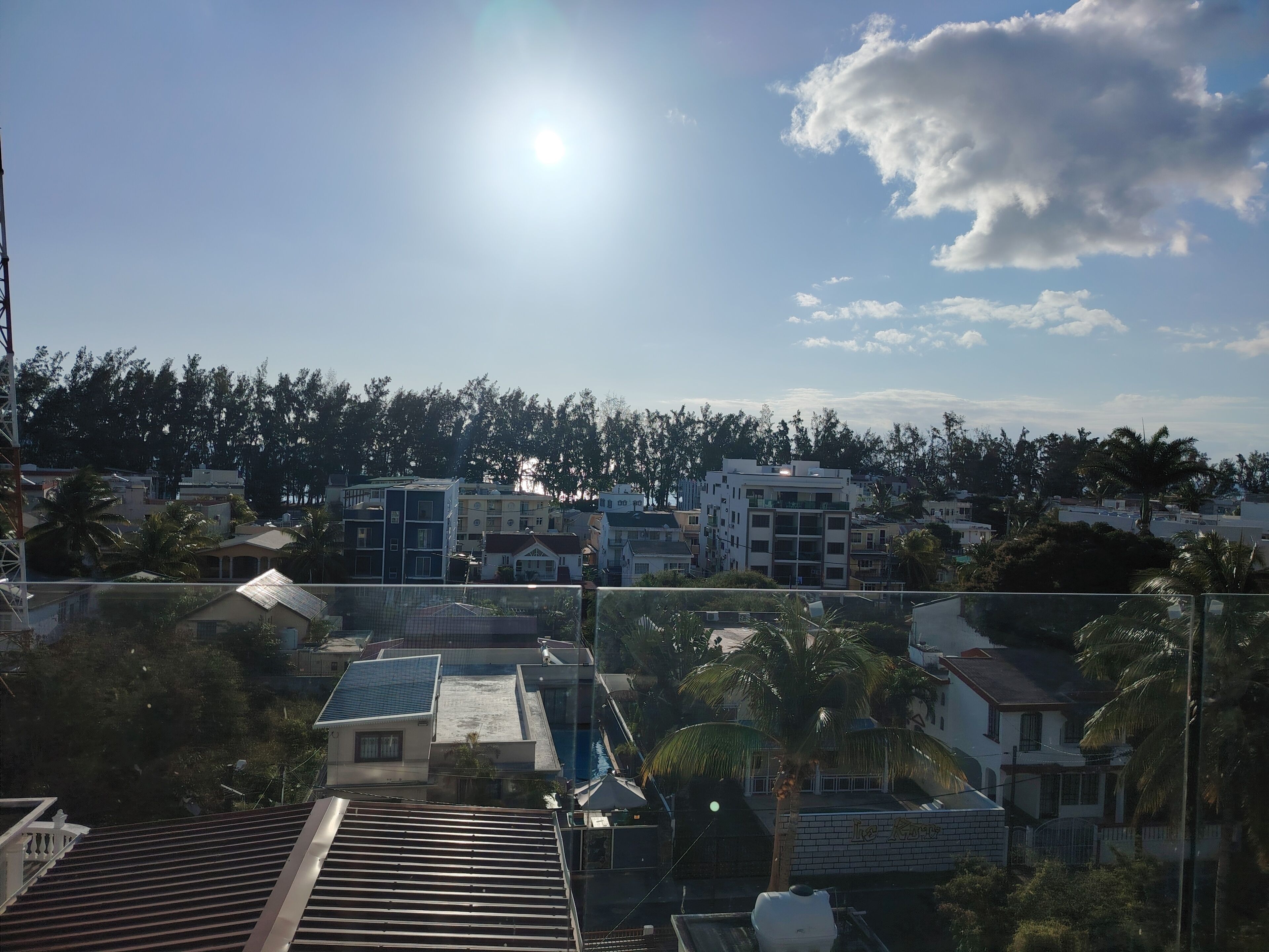 A residential area with modern buildings, a clear sky, and a sun shining.