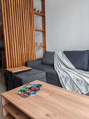 A modern living room with a sectional sofa, a wooden coffee table, and a built-in wooden shelving unit with decorative items.