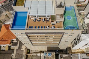 An aerial view of a rooftop with a swimming pool, sun loungers, and a basketball court. - Condo. w/ Pool and Gym 70 m From the Beach - SMA (Salvador)