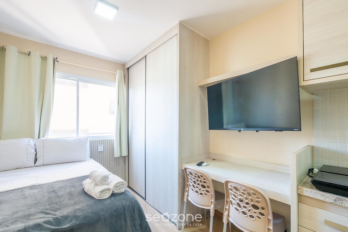 Une chambre d’hôtel comprenant un lit, un bureau avec deux chaises, un téléviseur à écran plat et une fenêtre avec des rideaux.