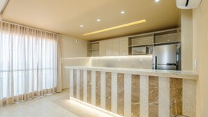 A modern kitchen with a marble countertop, built-in cabinets, and a stainless steel refrigerator. - Condo. w/ Pool and Gym 70 m From the Beach - SMA (Salvador)