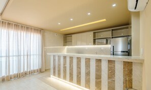 A modern kitchen with a marble countertop, built-in cabinets, and a stainless steel refrigerator. - Condo. w/ Pool and Gym 70 m From the Beach - SMA (Salvador)