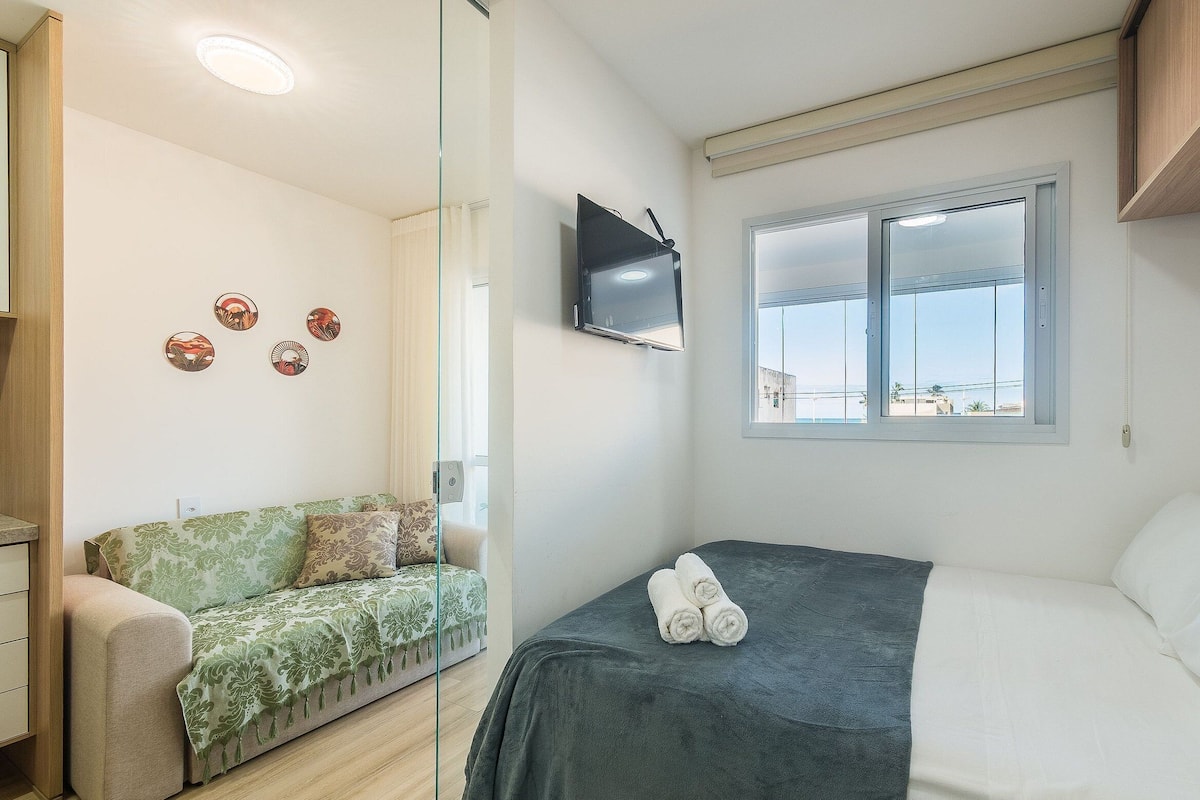 Une chambre avec un lit, un canapé, une télévision et une fenêtre donnant sur un beau paysage.