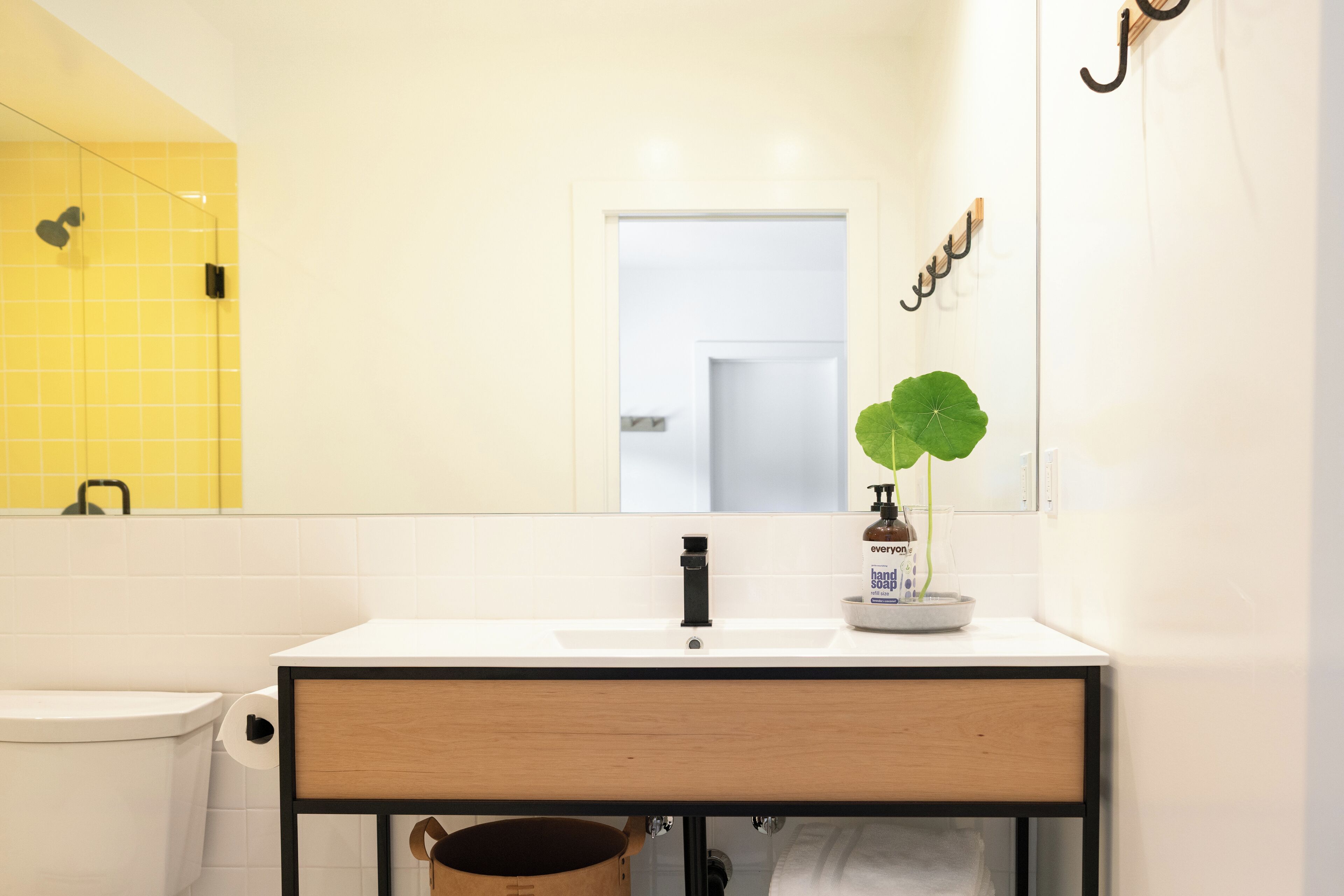 Une salle de bain avec un lavabo blanc, un miroir, des toilettes et un mur recouvert de carreaux jaunes.