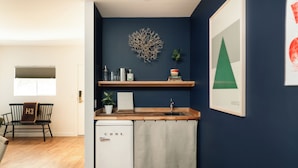 A compact kitchen with a white refrigerator, wooden countertop, and a blue accent wall. - Mendocino Cove (Fort Bragg)