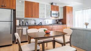 A modern kitchen with wooden cabinets, stainless steel appliances, and a dining area with a table and chairs.