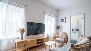 A living room with a television, a sofa, a chair, and a small table.
