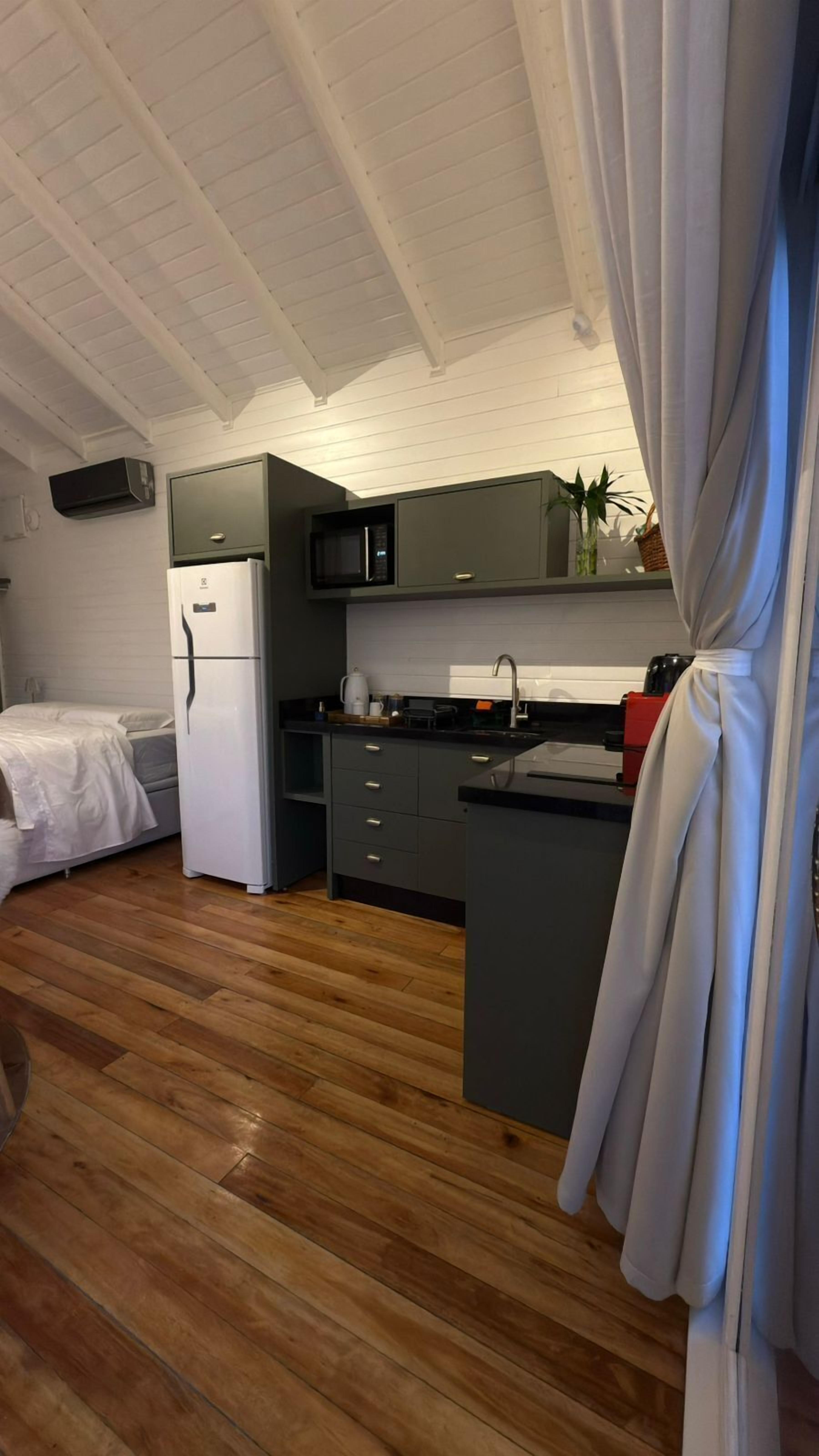Cocina compacta con refrigerador, microondas y pileta.