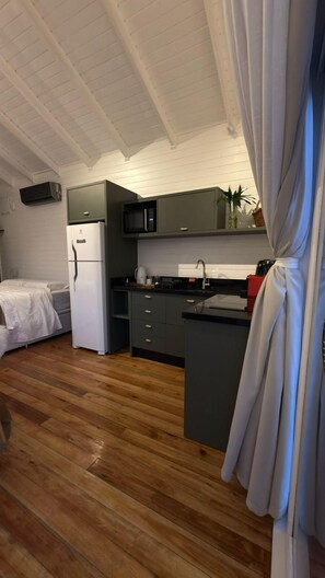 A compact kitchen with a refrigerator, microwave, and a sink. - Chalé Carmenere - Vila Chamonix (Urubici)