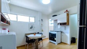 Una cocina compacta con una mesa de comedor, sillas, un refrigerador y una estufa.