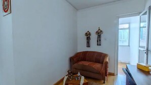 Una sala de estar con un sofá marrón, una mesita de madera con una botella y un adorno, y dos apliques de pared.