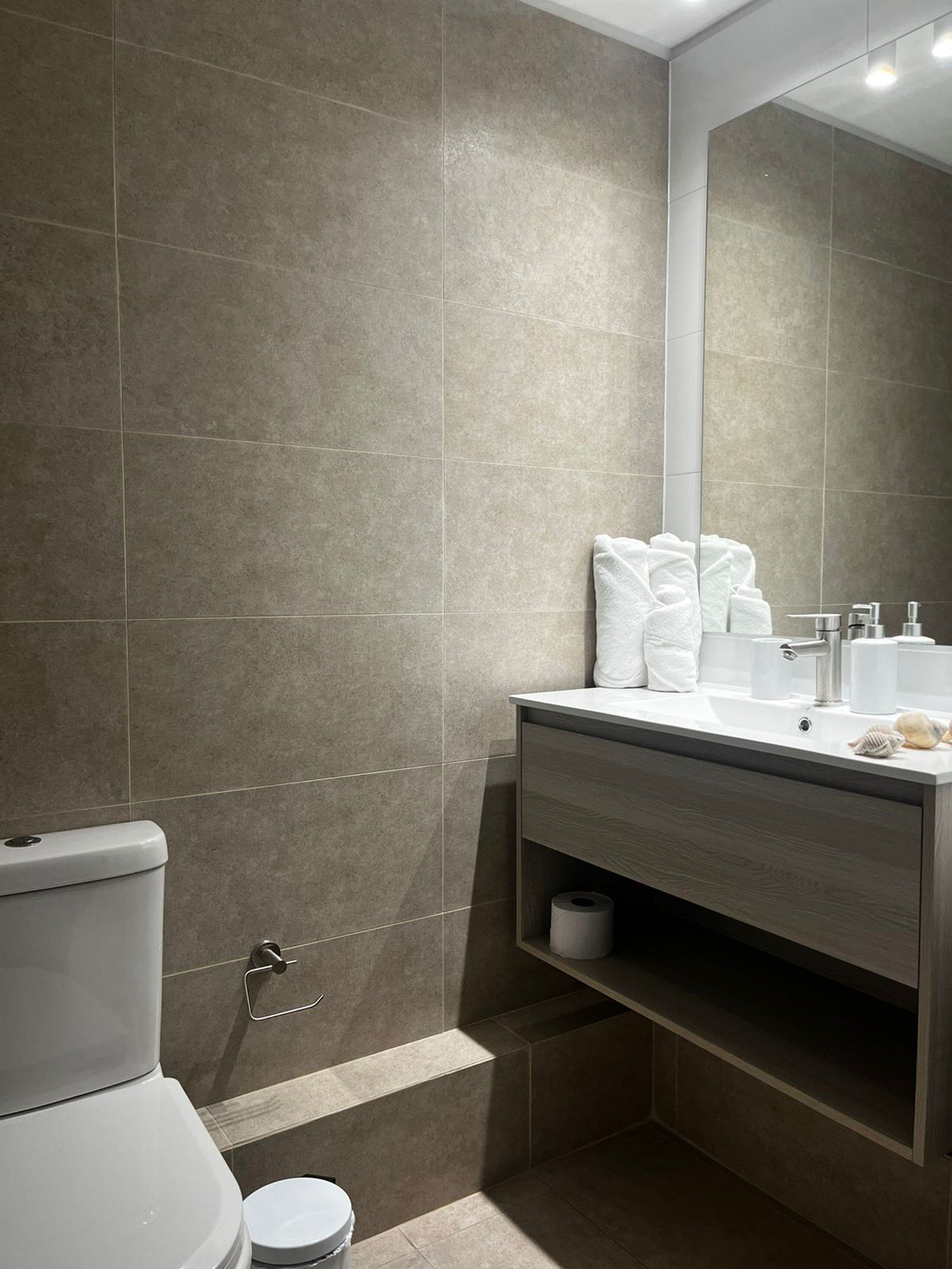 Un baño moderno con inodoro, lavabo y espejo.