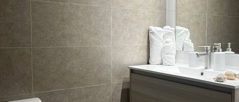Un baño moderno con inodoro, lavabo y espejo.