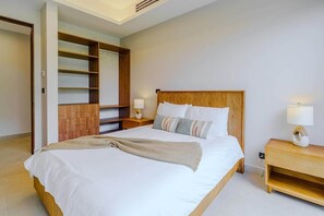 Une chambre moderne avec un grand lit, une tête de lit en bois, des tables de chevet avec des lampes et des étagères intégrées.