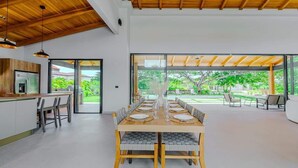 A modern dining area with a long wooden table set for six, surrounded by chairs with cushioned seats. - Casa Nimbu - Hacienda Pinilla (Hacienda Pinilla)