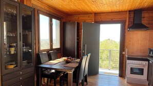 Un interior de fusta amb zona de menjador, un moble amb portes de vidre i cuina amb fogó.