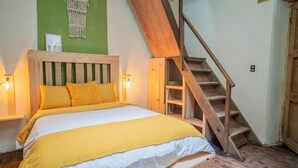 A bed with a wooden headboard, a yellow blanket, and a wooden staircase. - Co404 San Cristobal (San Cristóbal de las Casas)