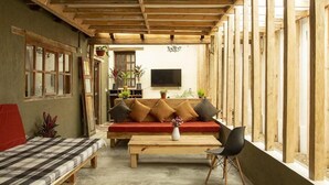 A cozy room with a wooden ceiling, a sofa with cushions, a coffee table, and a TV mounted on the wall. - Co404 San Cristobal (San Cristóbal de las Casas)