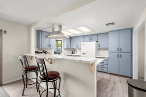 A modern kitchen with a central island, bar stools, and light blue cabinets.