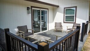 Un patio couvert, aménagé avec du mobilier d’extérieur, notamment des chaises et une table, et une porte-fenêtre coulissante donnant sur un espace intérieur.
