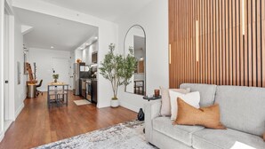 Una sala de estar moderna con un sofá gris, un espejo grande y un panel de pared de madera.