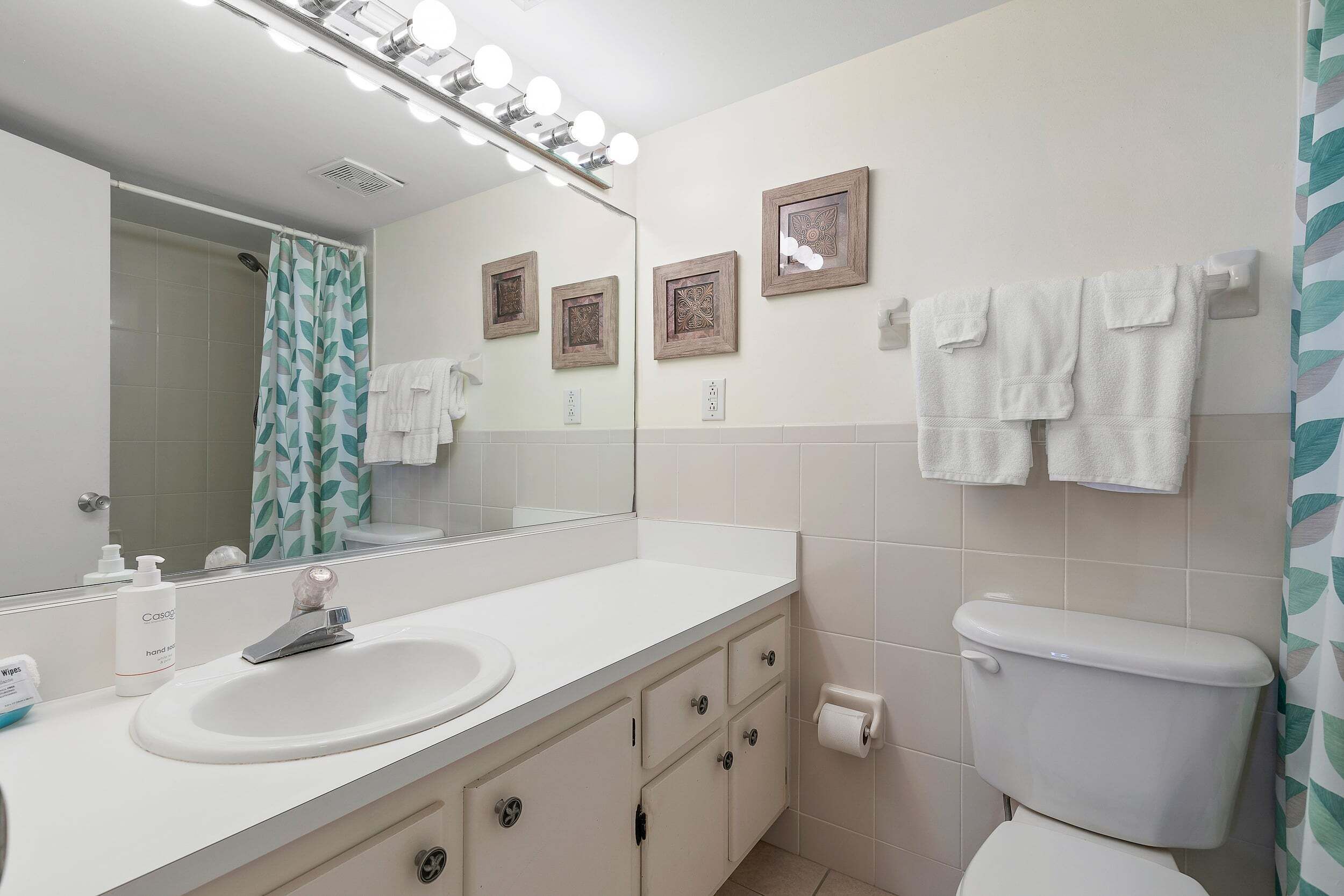 A bathroom with a sink, mirror, toilet, and towel rack.