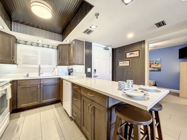 A modern kitchen with a central island, bar stools, and a backsplash. - Oceania II (New Smyrna Beach)