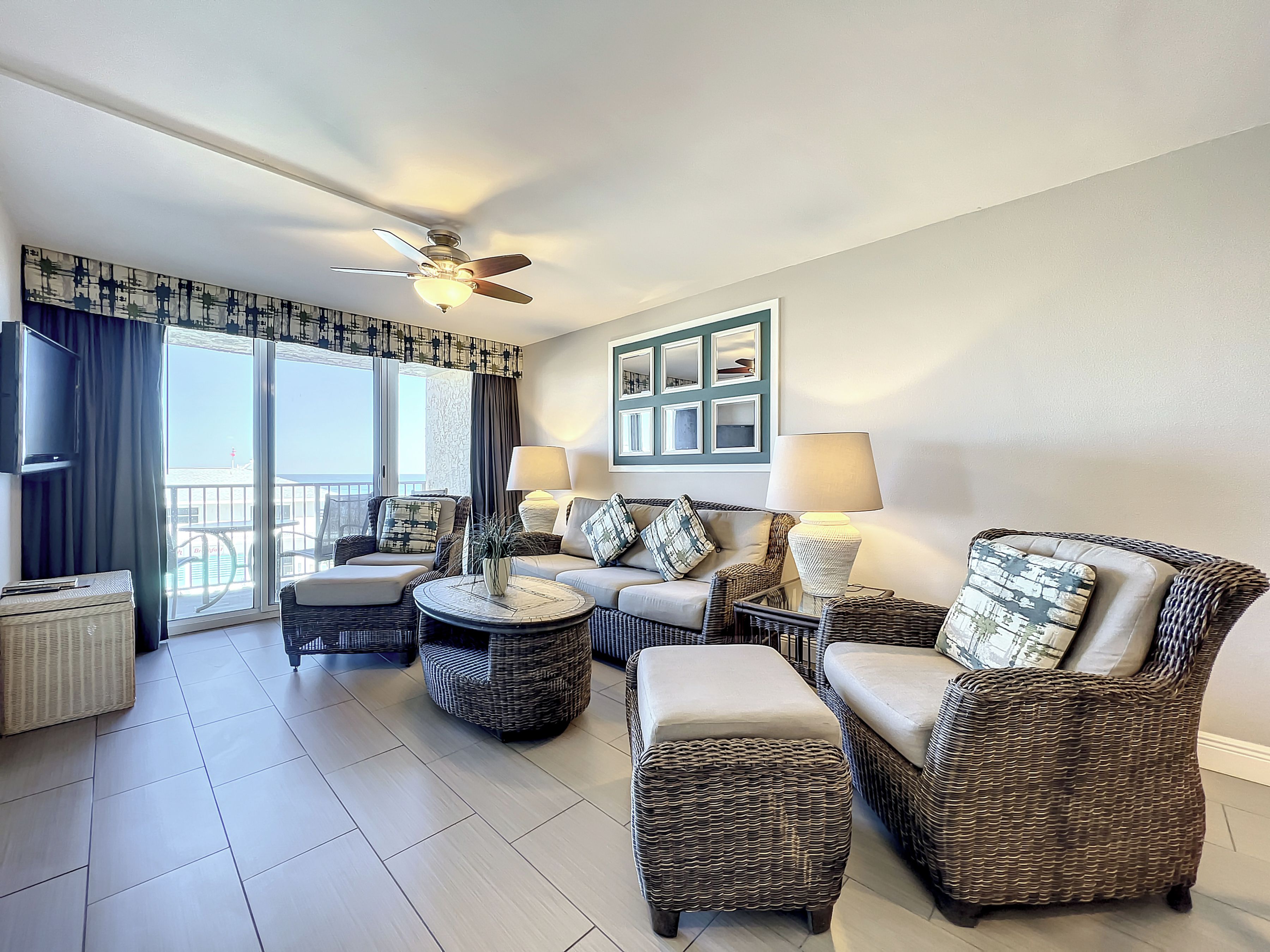 A spacious living room with wicker furniture, a ceiling fan, and a view of the outdoors.