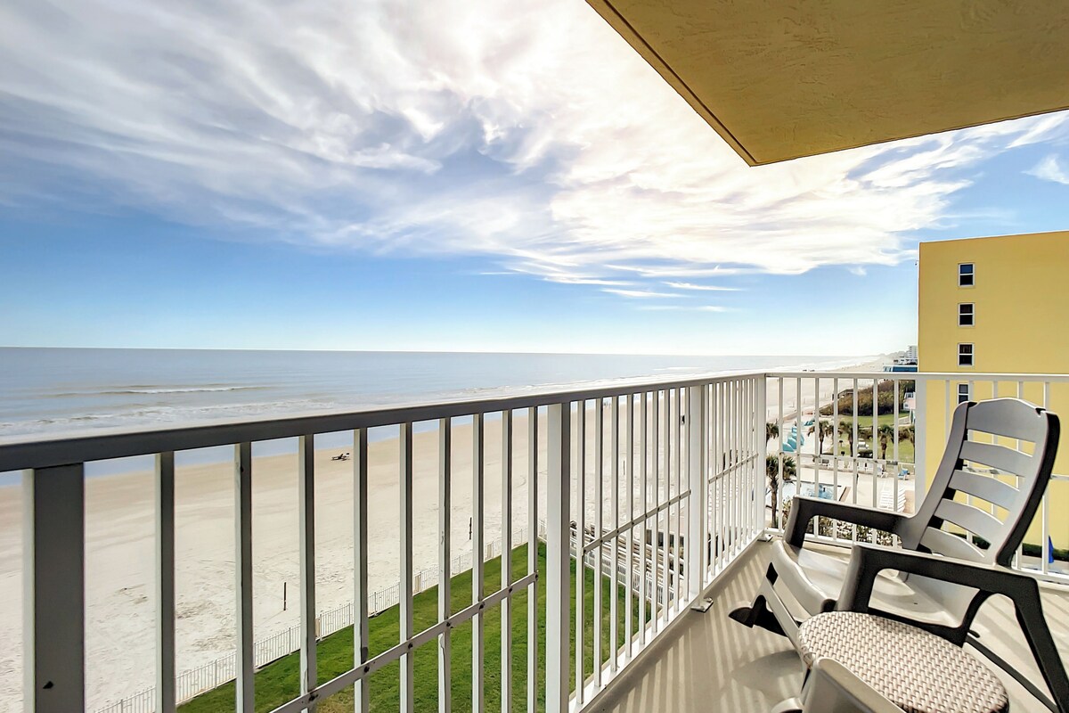 A balcony with a view of the beach and ocean.