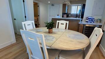 Een eetgedeelte met een ronde tafel, witte stoelen en een hanglamp.