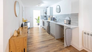 Une cuisine moderne dotée d’un plan de travail en bois, d’appareils électroménagers intégrés et donnant sur l’espace repas.