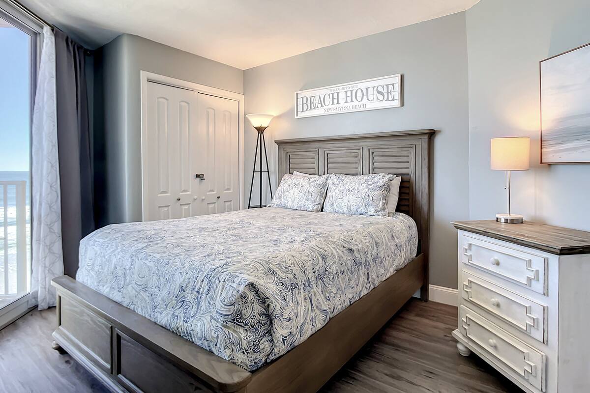 Un dormitorio con cama, mesita de noche, lámpara, cómoda y un letrero que dice "Beach House".