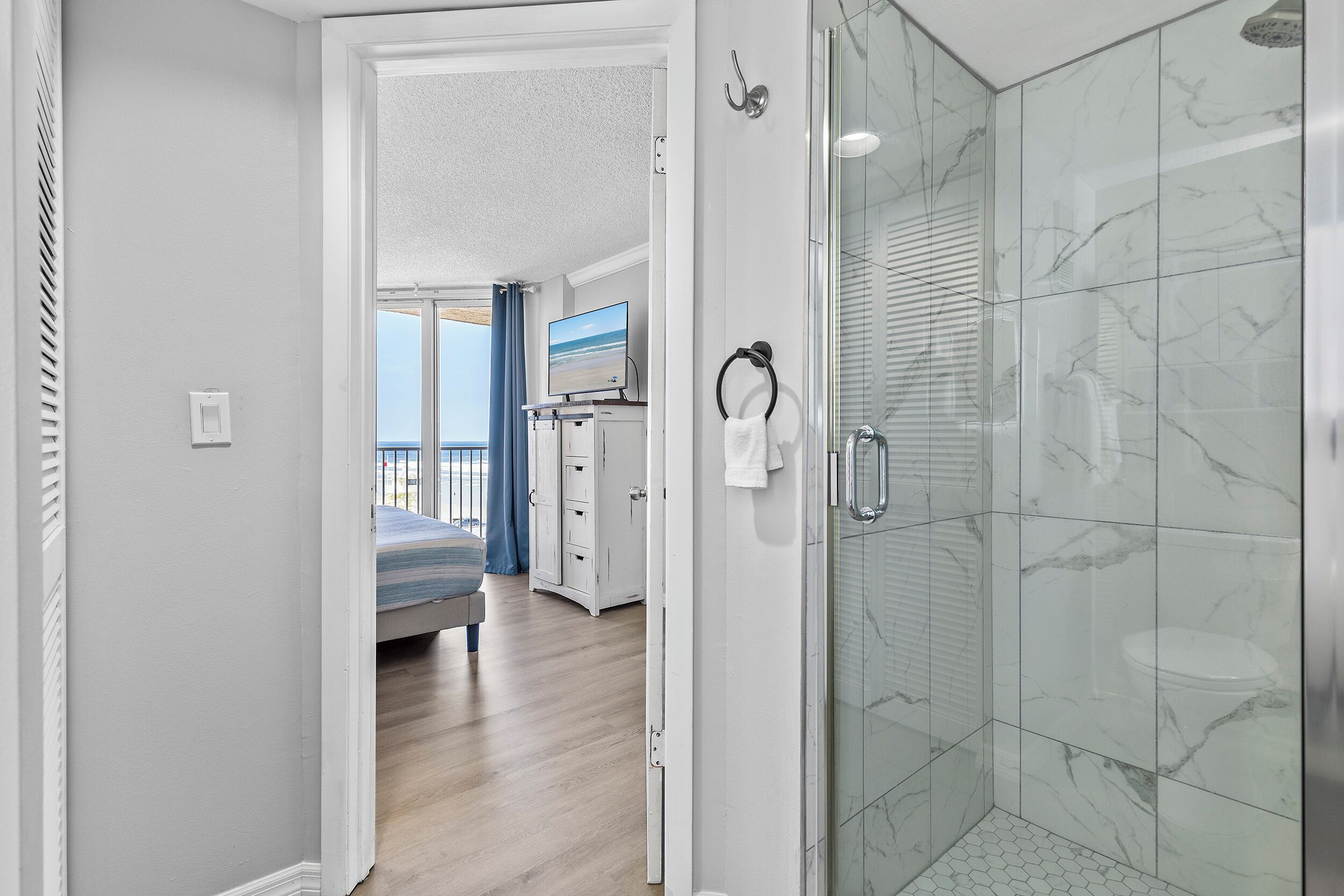 Un baño moderno con ducha de vidrio, lavamanos blanco y un aro para toallas.