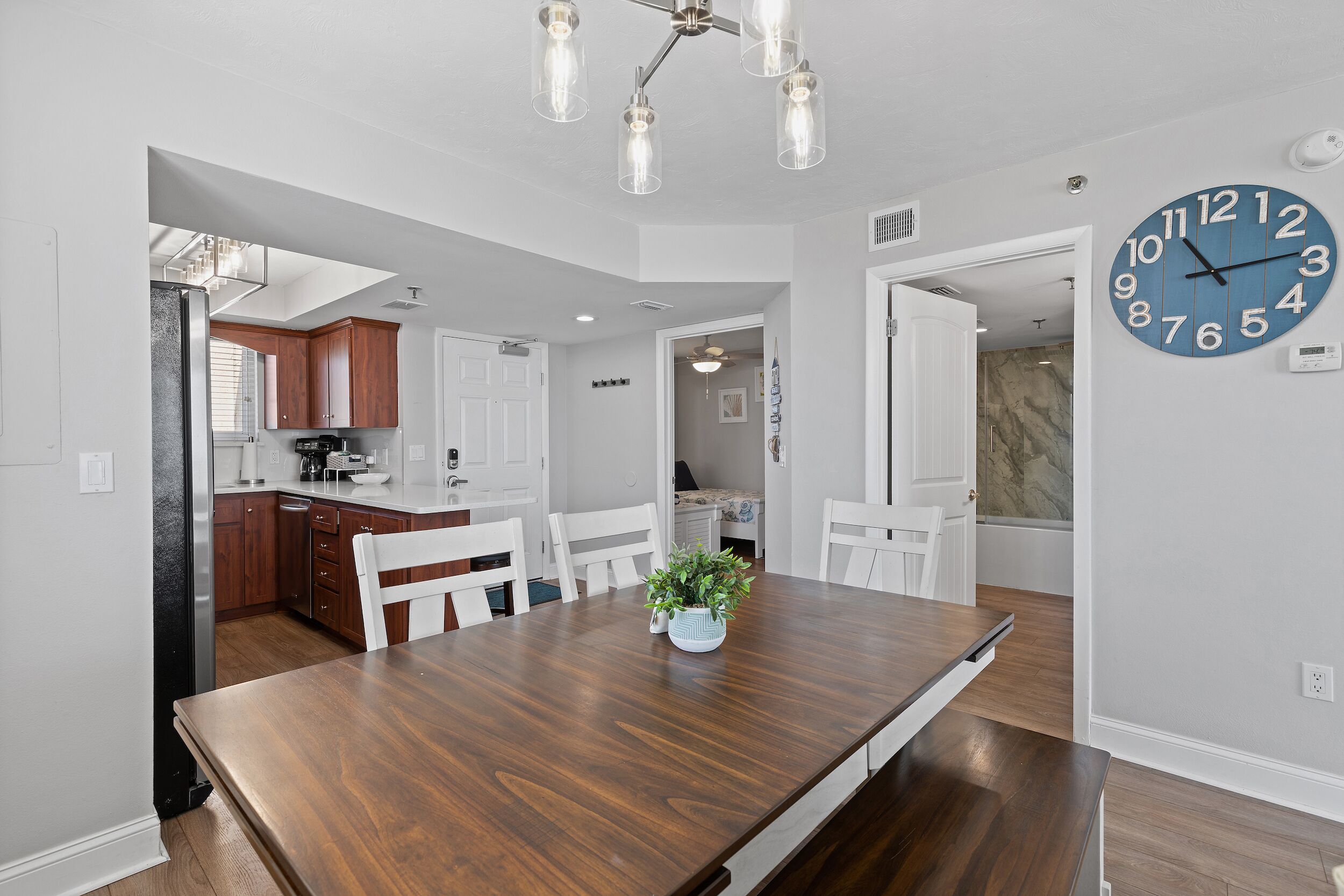 Una cocina moderna con armarios de madera, una mesa de comedor con sillas y un reloj de pared grande.