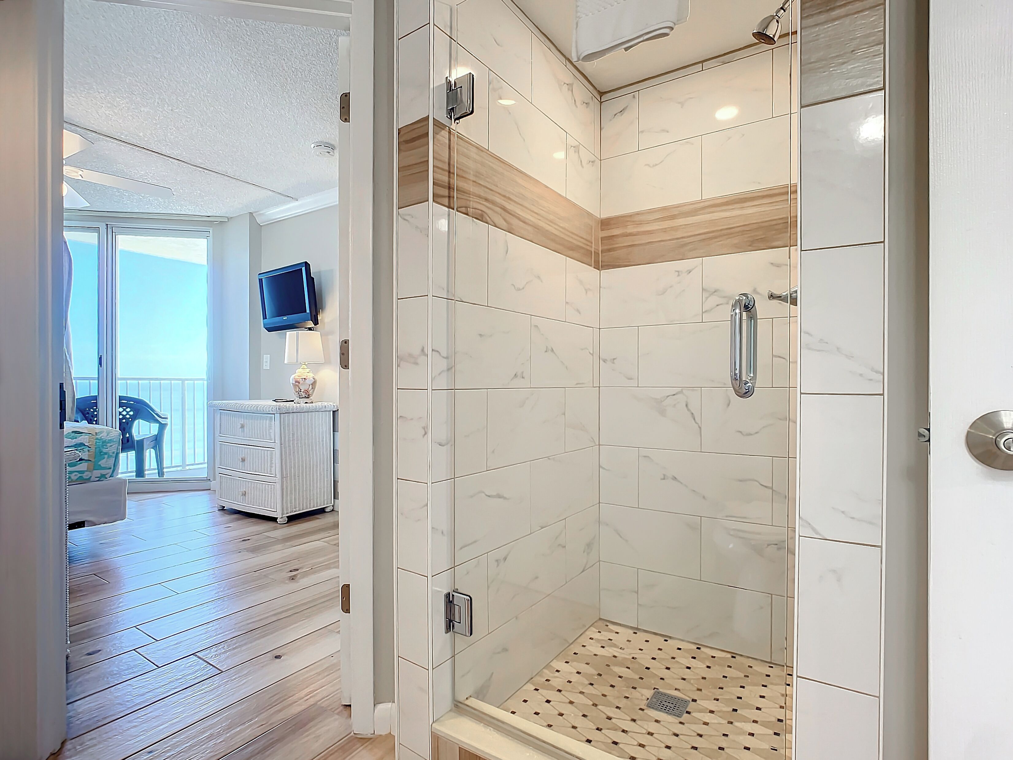 Une salle de bain moderne avec une douche à parois de verre, des carreaux de marbre et un mur d’accent en bois.
