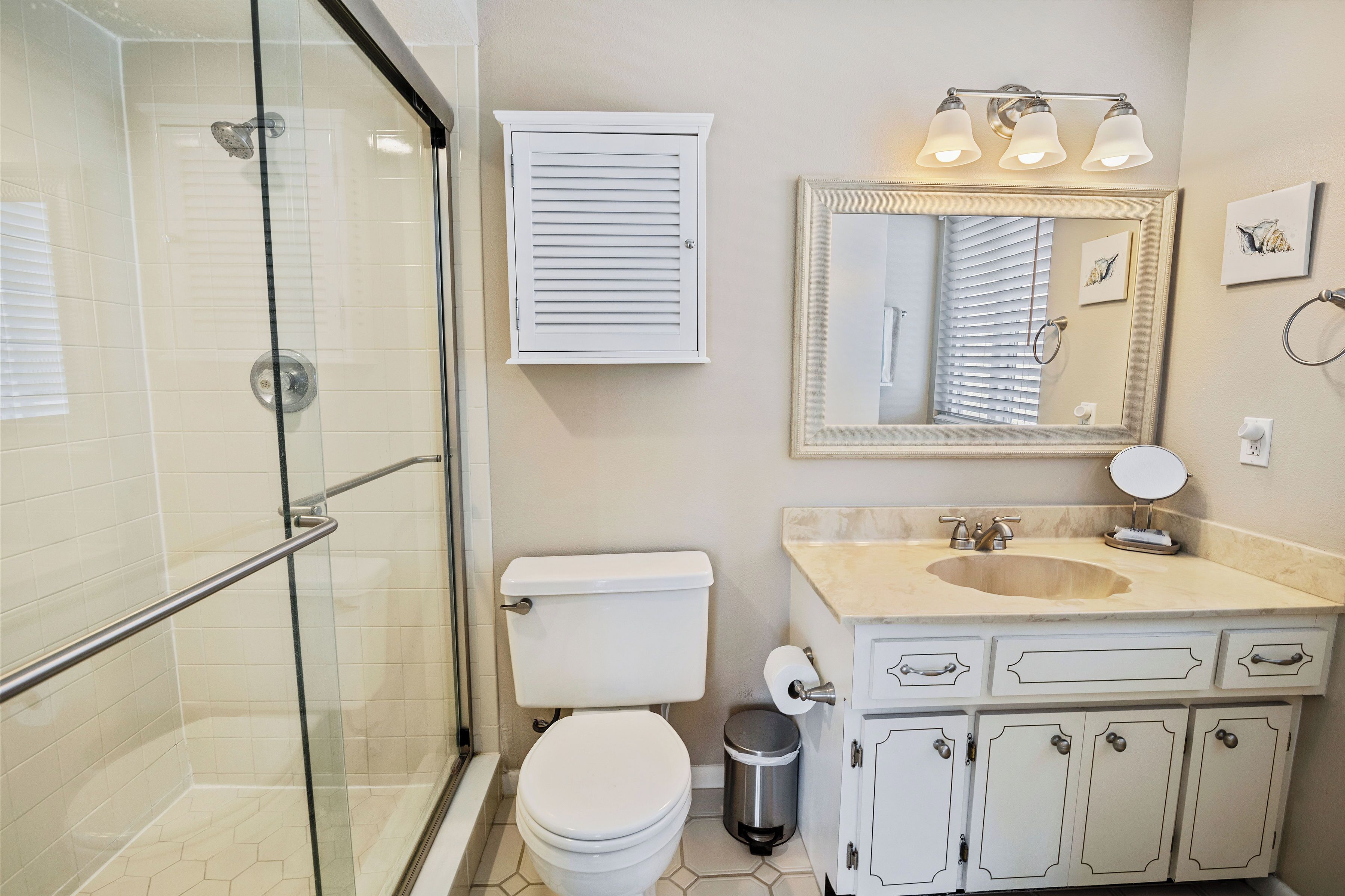 Une salle de bain avec une douche à parois de verre, des toilettes, un lavabo avec un meuble-vasque et un miroir avec éclairage.