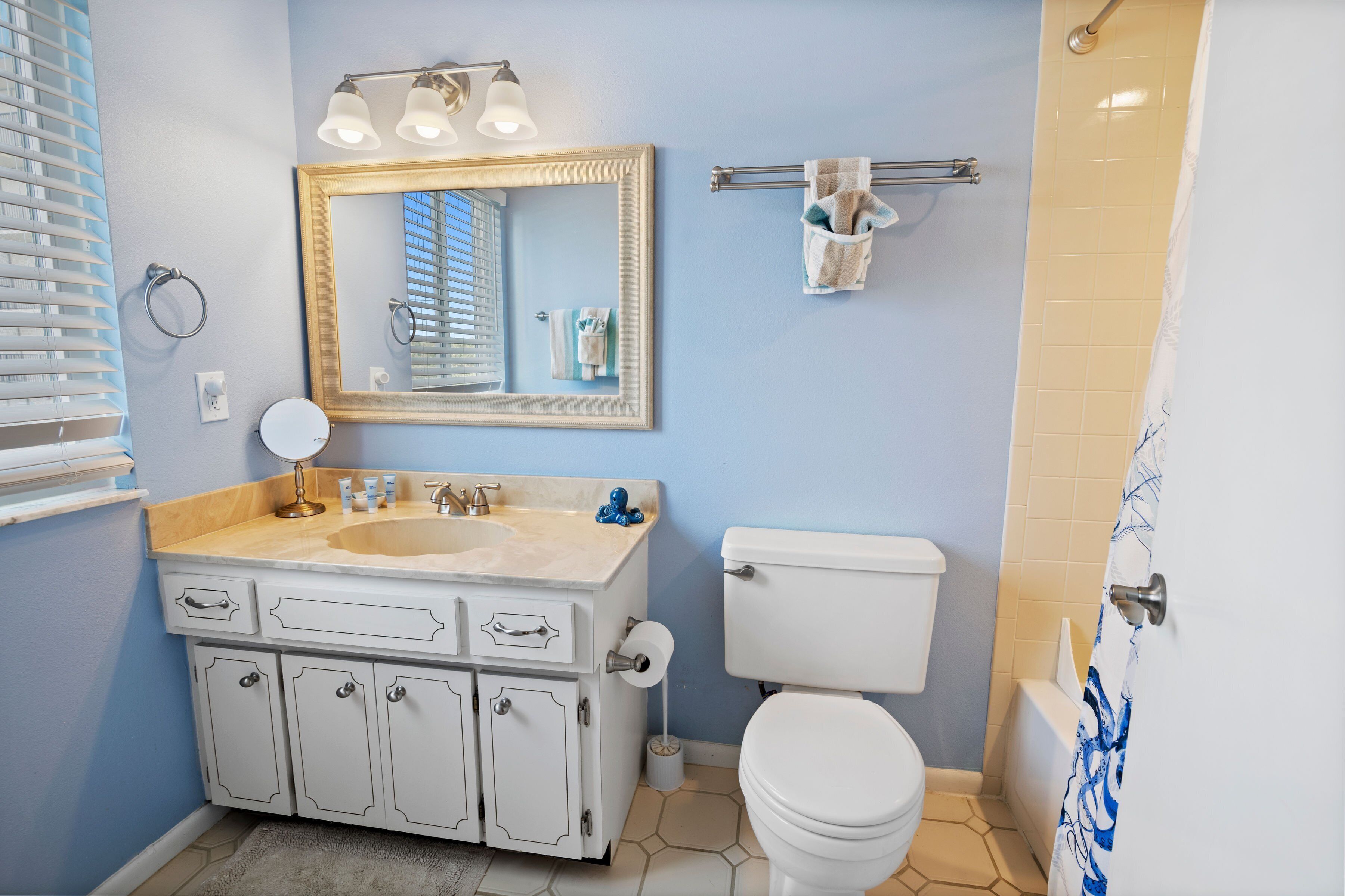 Une salle de bain équipée d’un lavabo, d’un miroir, de toilettes et d’un porte-serviettes.