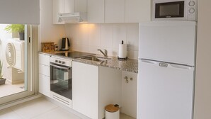 Una cocina moderna con armarios blancos, horno empotrado, microondas y fregadero.