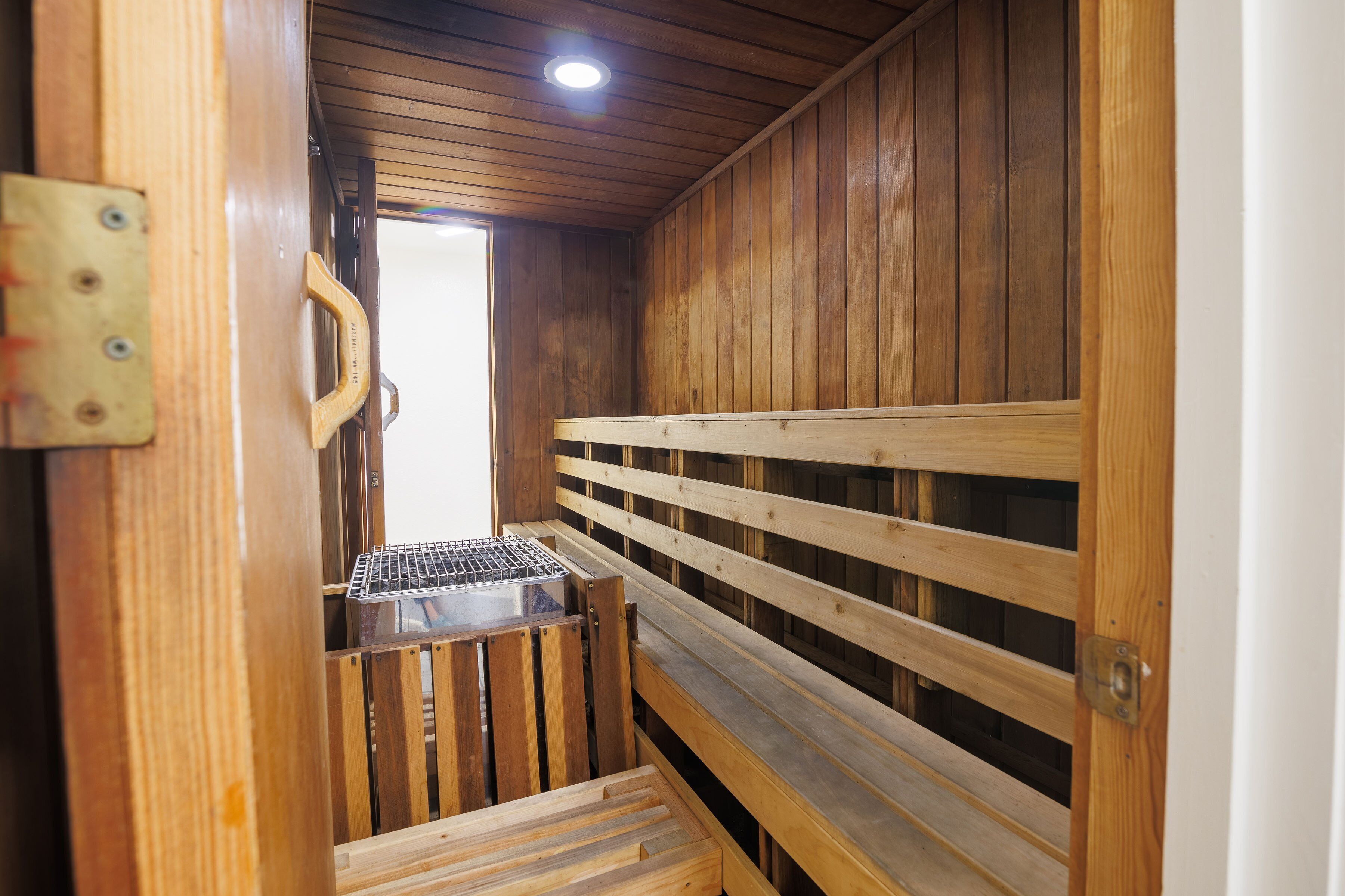 A wooden sauna with a bench and a metal grate.