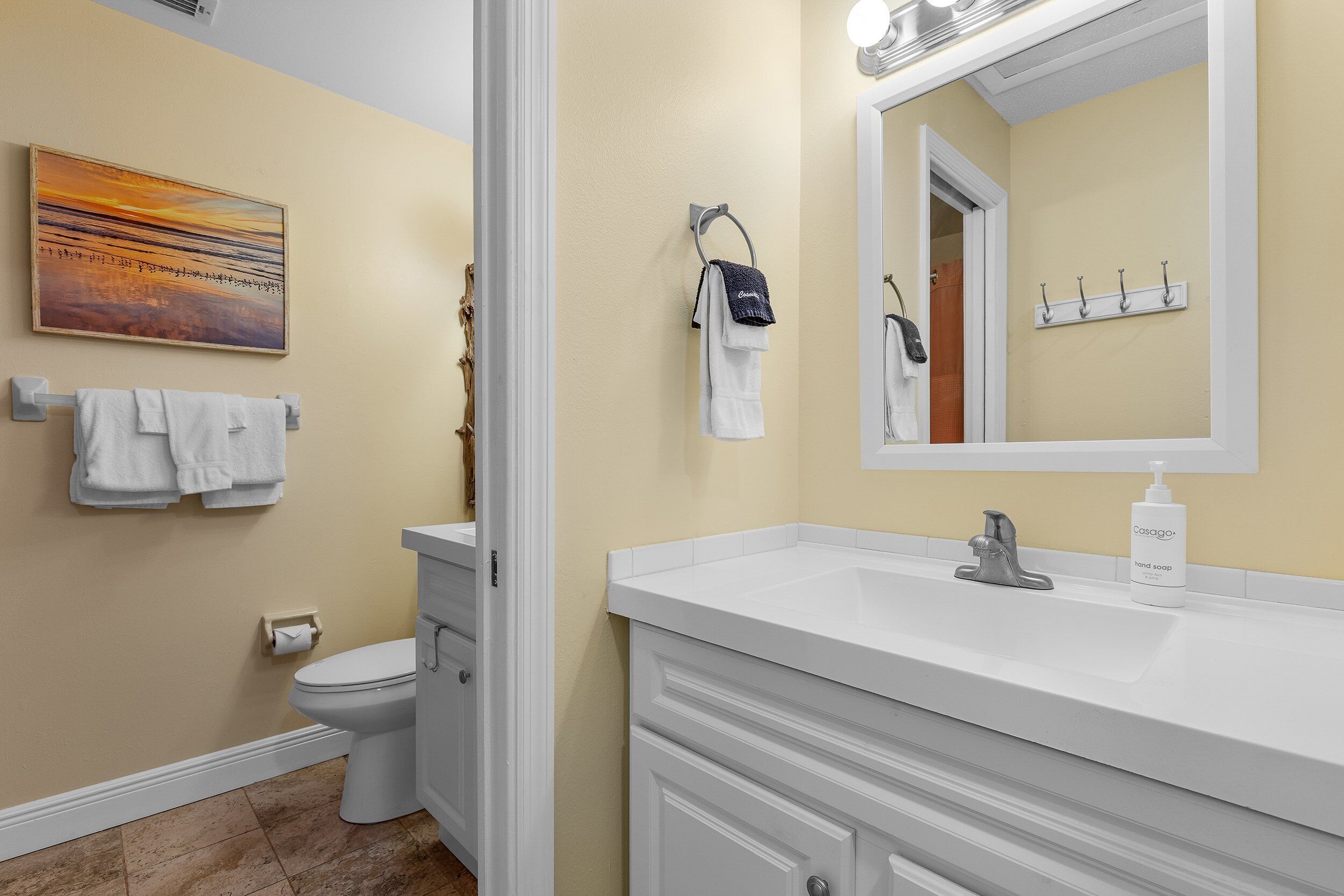 Een badkamer met een wit wastafel, een spiegel, een handdoekhouder en een toilet.