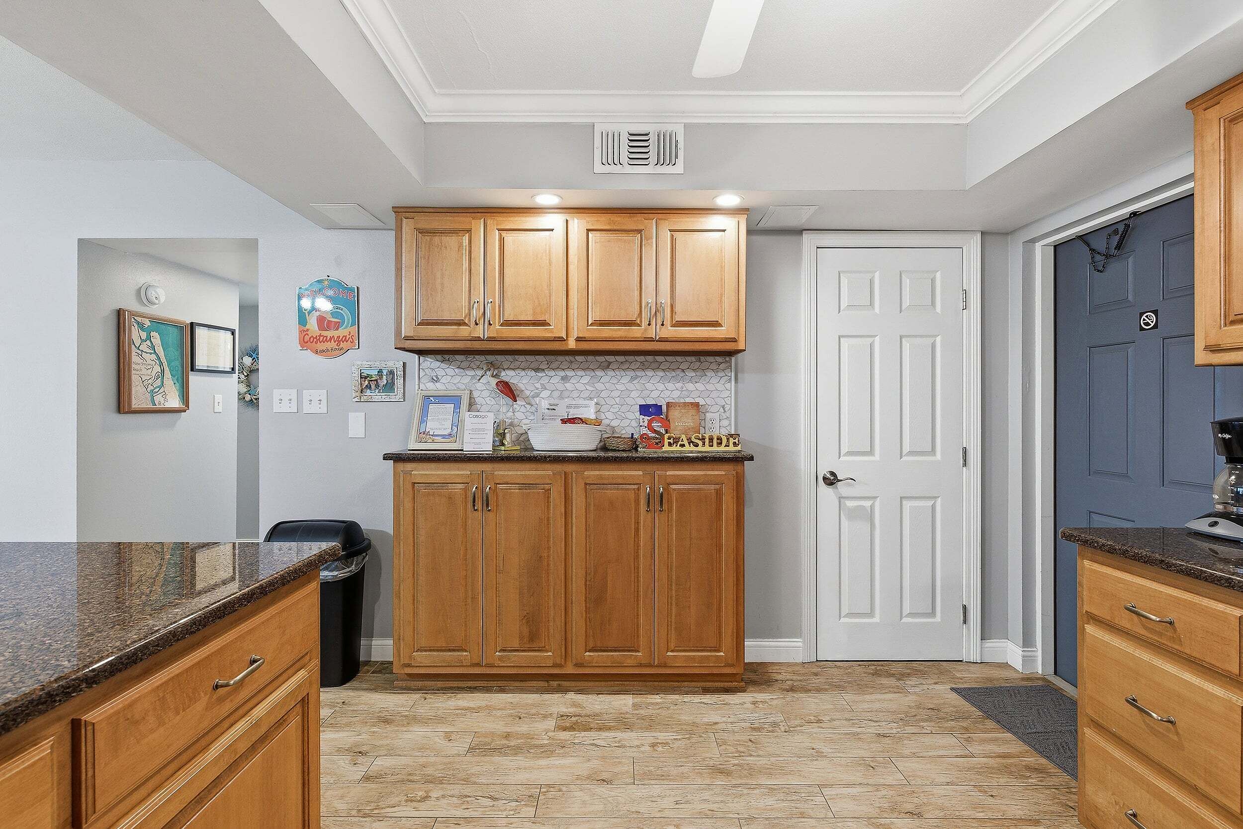 A kitchen with wooden cabinets, a white door, and a countertop with various items.