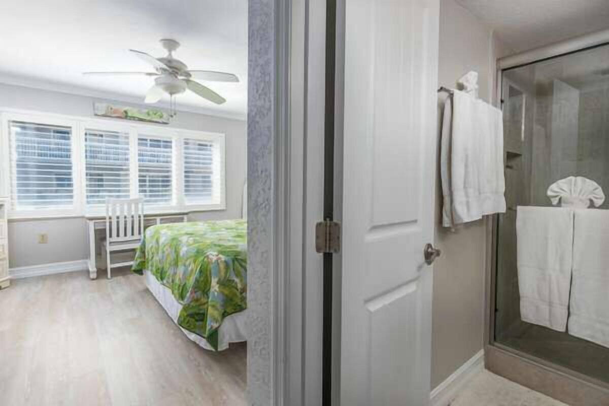 A bedroom with a bed, a desk, and a window with blinds.